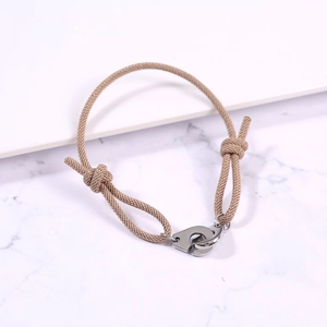 Detail view of khaki woven rope bracelet with adjustable knots and stainless steel handcuffs