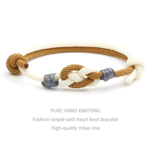 Close-up of handmade woven heart knot bracelet with white and khaki Milanese cord detail