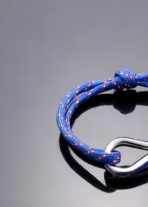Detail of blue woven rope bracelet featuring a silver U-shaped metal buckle on black background