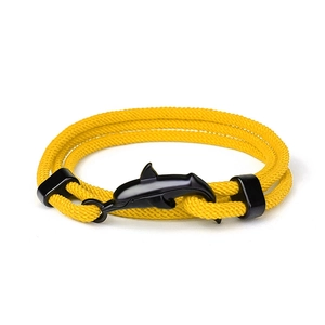 Dettaglio macro del bracciale in corda intrecciata gialla con ciondolo a delfino nero
