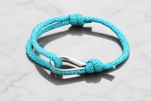 Close-up of hand-woven lake blue sports bracelet with polished metal U-hook clasp