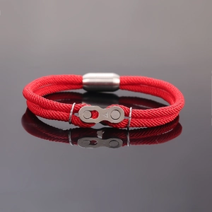 Détail macro du bracelet en corde tressée rouge avec élément de chaîne en argent brossé