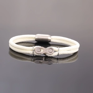 Gros plan d'un bracelet en corde tressée blanche avec maillon argenté et fermoir magnétique