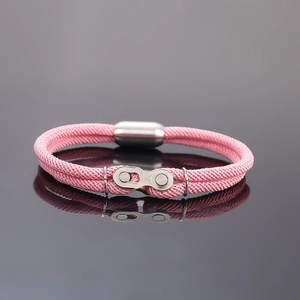 Détail du bracelet tressé rose avec maillons de chaîne de vélo en métal poli