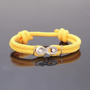 Gros plan d'un bracelet en corde tressée jaune avec une boucle de chaîne de vélo en métal