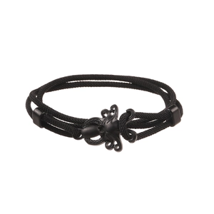 Dettaglio del ciondolo a forma di polpo nero in metallo su bracciale in corda intrecciata