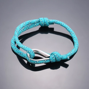 Detail of teal braided nylon bracelet with adjustable silver metal hook on mirror surface