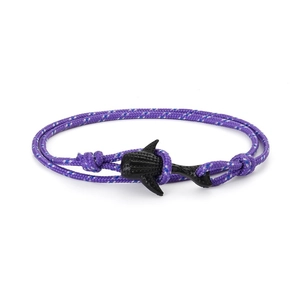 Détail macro du bracelet en corde tressée violette avec pendentif requin-baleine noir
