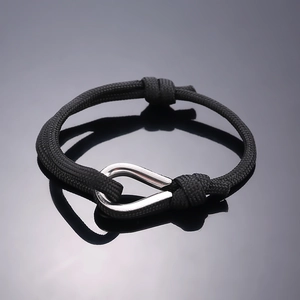 Detail of minimalist black woven cord bracelet with polished silver U-shaped metal ring
