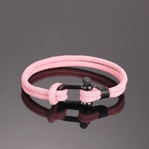 Detail eines rosa geflochtenen Segeltau-Armbands mit schwarzem U-förmigem Schäkelverschluss