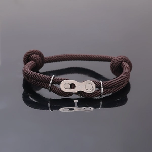 Vue macro d'un bracelet tressé marron foncé avec boucle argentée et reflet miroir élégant
