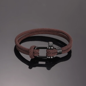 Detail eines dunkelbraun geflochtenen Nylonarmbands mit mattem schwarzem Hufeisenverschluss