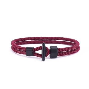 Detail eines weinroten geflochtenen Doppelarmbands mit mattschwarzem T-Verschluss aus Metall