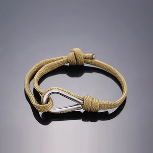 Macro detail of khaki paracord braided bracelet with silver metal U-shaped buckle closure