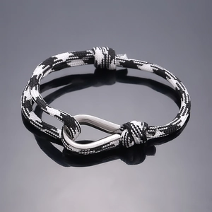 Detail of nautical black and white braided rope bracelet with silver metal U-shackle clasp
