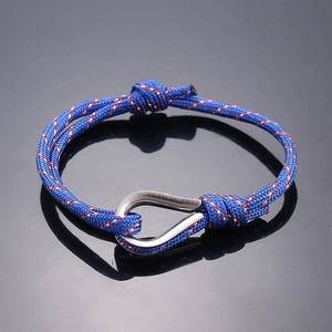 Detail of nautical braided rope bracelet with red accents and silver horseshoe shackle