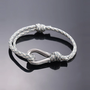 Macro detail of nautical braided bracelet with silver stainless steel shackle on black glass