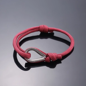 Detail of red braided nylon rope bracelet featuring a polished silver U-shape metal buckle