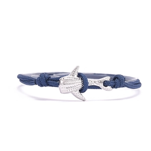 Détail du bracelet tressé bleu avec un pendentif requin-baleine argenté aux motifs précis