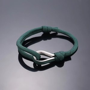 Detail of dark green braided rope bracelet with a polished silver U-shaped metal clasp