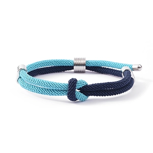Detail van een blauwe gevlochten touwarmband met zilveren metalen ring en sluitingen