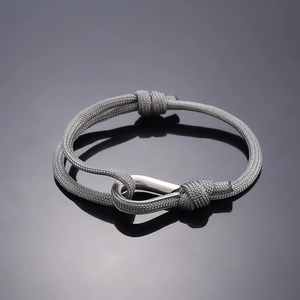 Close-up of minimalist grey woven rope bracelet with polished silver U-shaped metal clasp