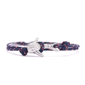 Détail du bracelet en corde nautique avec breloque requin argentée et cordon tressé marine