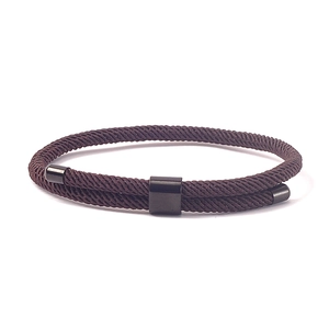 Detail van donkerbruine gevlochten armband met dubbele laag en gepolijste zwarte metalen sluiting