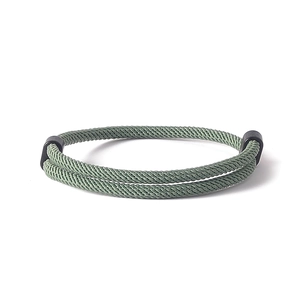 Close-up of sage green braided rope bracelet with matte black connectors and adjustable knots