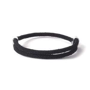 Detail of hand-woven black cord bracelet with silver anchor buckle on a white backdrop