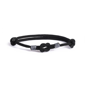 Dettaglio del bracciale nero intrecciato a nodo concentrico con chiusura regolabile
