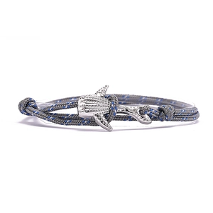 Gros plan d'un pendentif requin-baleine sur un bracelet tressé gris avec détails bleus
