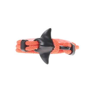 Detail of coral orange braided rope bracelet with a matte black manta ray charm detail