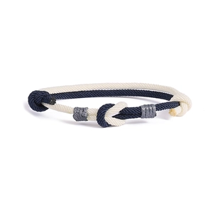 Dettaglio ravvicinato di un bracciale intrecciato nautico con nodi blu marino e beige