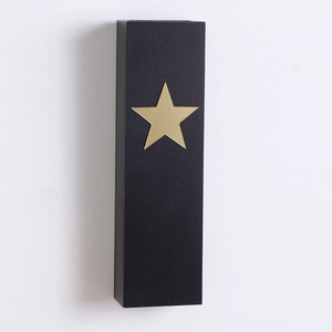 Detail view of rectangular black wooden shelf featuring a minimalist gold star ornament
