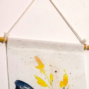 Detail of bohemian hanging art showing fabric texture, wooden pole, and tassel rope