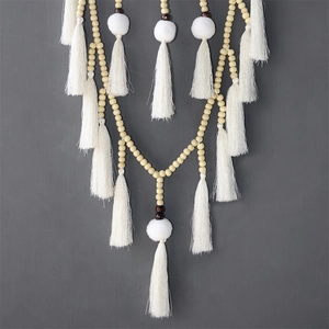 Détail des glands en textile blanc et des perles en bois sur un attrape-rêves fait à la main