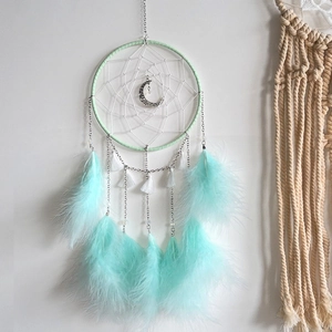 Detail of bohemian dream catcher featuring mint green feathers and silver moon pendant