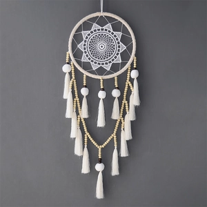 Détail d'un attrape-rêves blanc avec dentelle, perles en bois et pompons doux