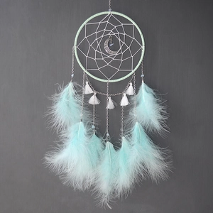 Detail of mint green and white dreamcatcher with hollow moon pendant and soft feathers