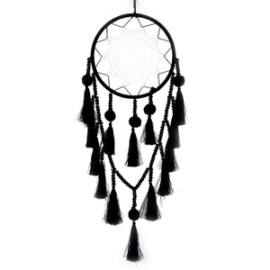 Détail d'un attrape-rêves noir montrant des pompons, des perles et un motif de filet blanc