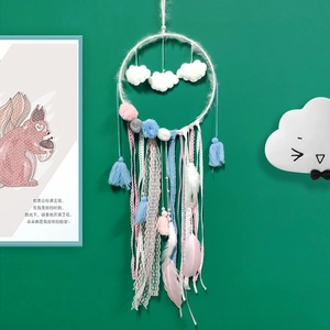 Detail of dream catcher wall decor with white clouds, pink feathers and lace ribbons