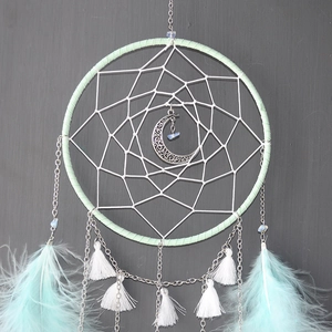 Detail of light green dreamcatcher with a silver crescent moon and soft feathers