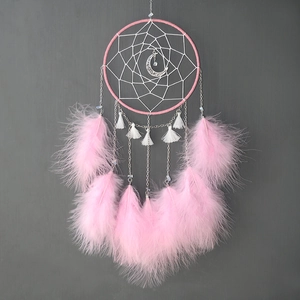 Detail of pink feather dreamcatcher featuring white woven web and a silver moon pendant