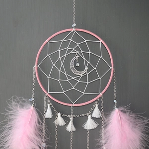 Detail of handmade moon dream catcher with pink feathers and silver moon pendant