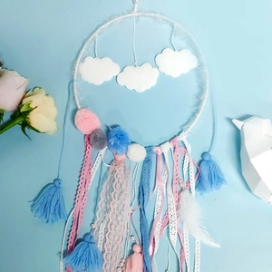 Detail of dream catcher with white clouds, pastel lace ribbons and colorful pom-poms