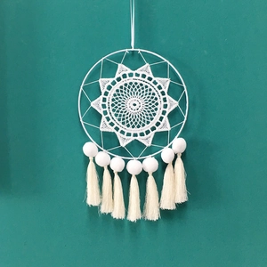 Capteur de rêves blanc fait main avec pompons et franges sur fond vert foncé