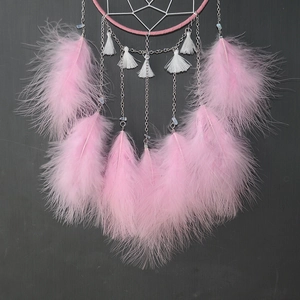 Close-up of pink dreamcatcher with delicate feathers and hanging silver metal chains