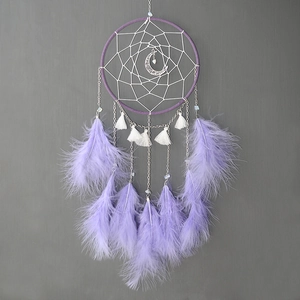Detail of handmade moon dream catcher featuring purple feathers and silver moon pendant