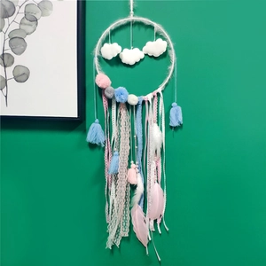 Detail of dream catcher with white clouds, pastel pom poms, feathers and lace ribbons
